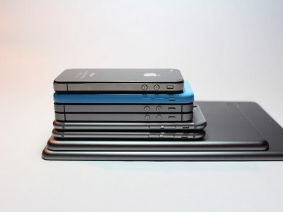 Many mobile phones and tablets stacked on one another.